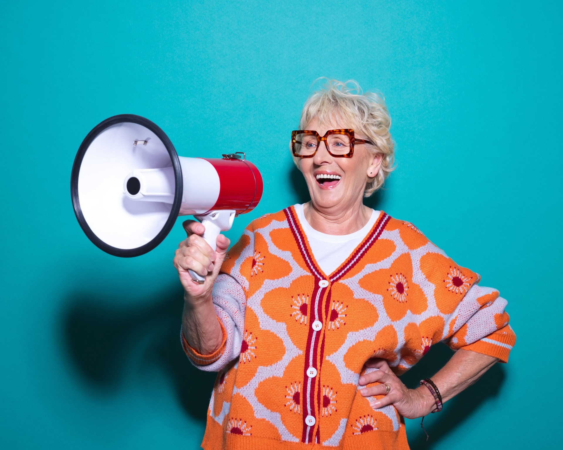 Portrait of cheerful senior woman talking into megaphone